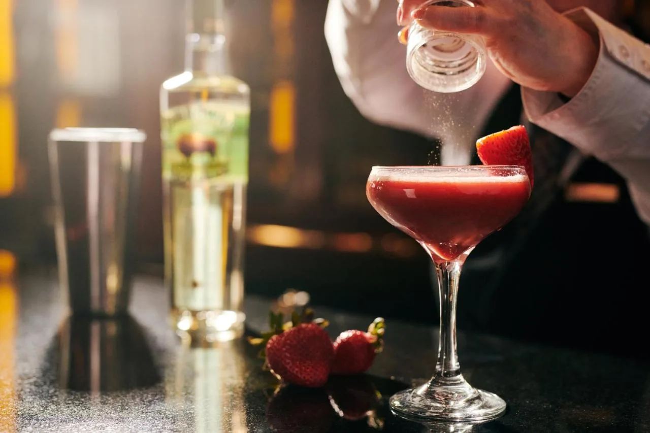 a bartender making a strawberry cocktail in a martini glass at Hard Days Night Hotel Liverpool in Liverpool