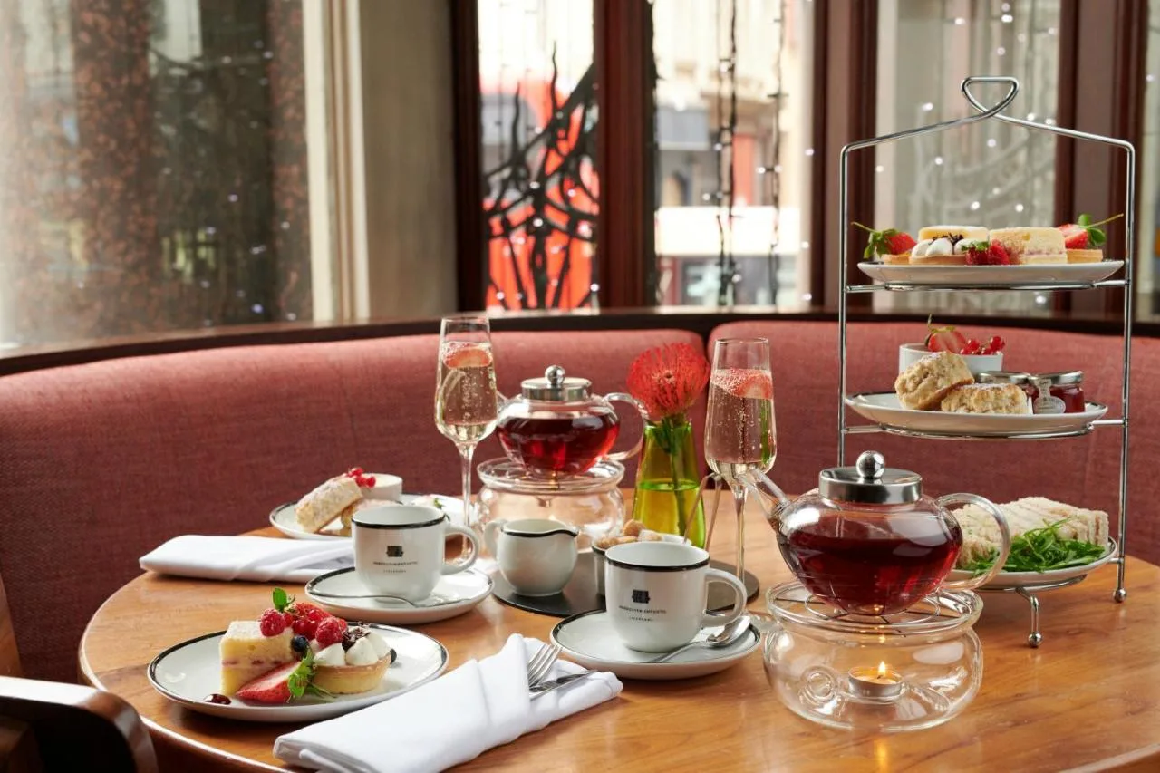 a table with plates of food and glasses of wine at Hard Days Night Hotel Liverpool in Liverpool